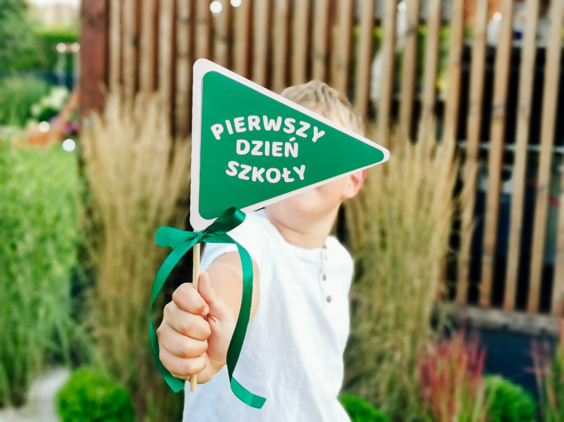 chłopiec z zieloną flagą pierwszy dzień szkoły