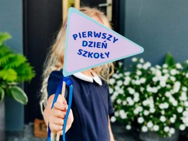 dziewczynka z flagą z napisem pierwszy dzień szkoły